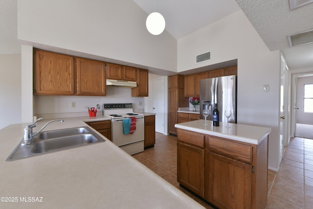 kitchen featuring stainless steel refrigerator with ice dispenser, under cabinet range hood, visible vents, a sink, and white range with electric cooktop