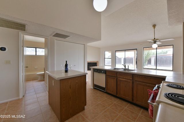 kitchen with white appliances, a center island, visible vents, a tile fireplace, and a sink