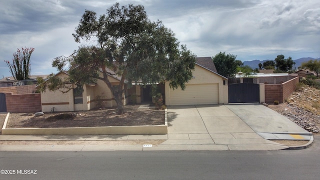 view of property hidden behind natural elements featuring an attached garage, fence, concrete driveway, stucco siding, and a gate
