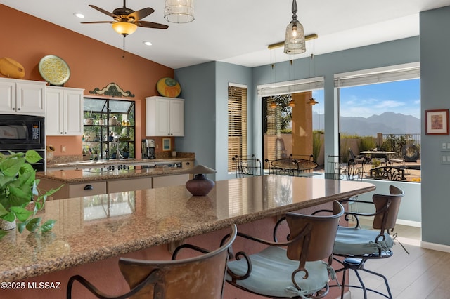 kitchen with pendant lighting, black microwave, white cabinetry, a mountain view, and a healthy amount of sunlight