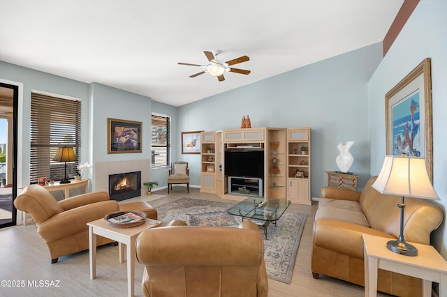 living room featuring ceiling fan, a fireplace, light hardwood / wood-style floors, and vaulted ceiling