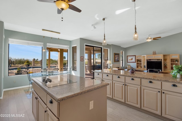 kitchen featuring vaulted ceiling, a kitchen island, decorative light fixtures, light stone countertops, and black electric cooktop