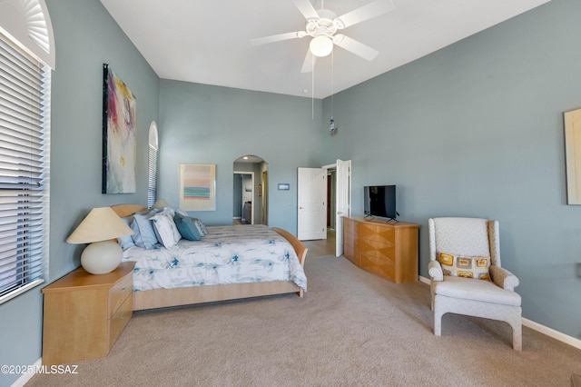 carpeted bedroom with ceiling fan and a high ceiling