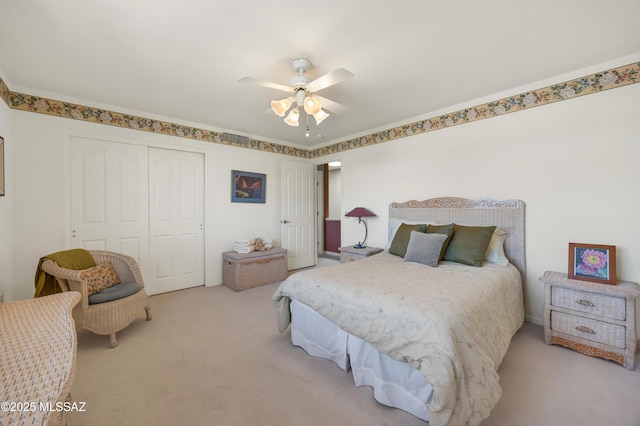 bedroom with ornamental molding, light carpet, ceiling fan, and a closet