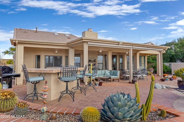 back of house with outdoor lounge area, a patio area, and a bar