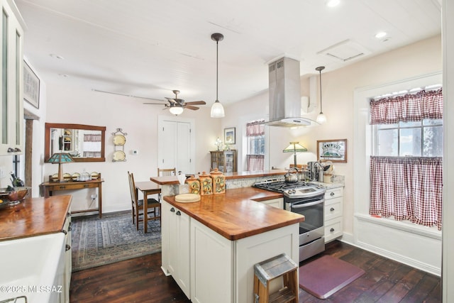 kitchen featuring decorative light fixtures, white cabinets, island exhaust hood, and stainless steel gas range