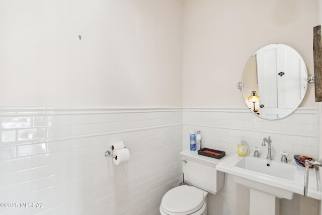 bathroom featuring sink, toilet, and tile walls