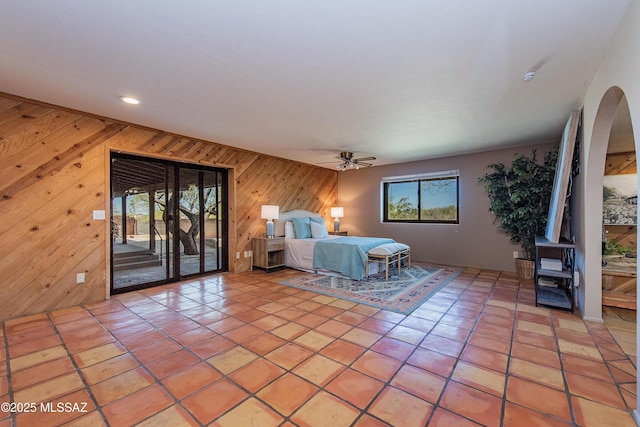 unfurnished bedroom featuring ceiling fan, light tile patterned floors, access to outside, and wooden walls