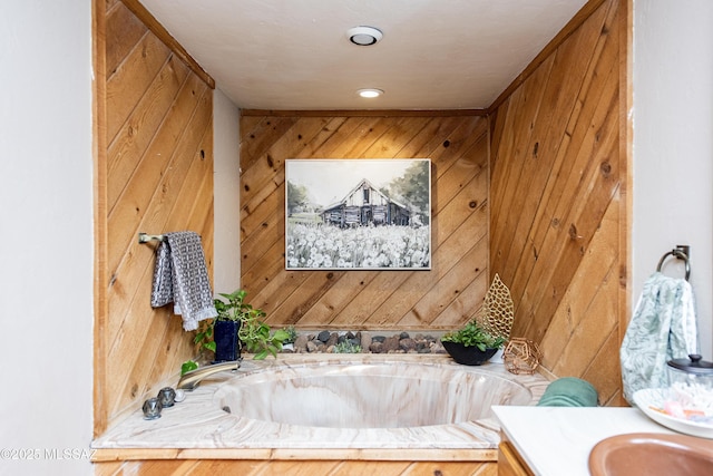 bathroom with a tub, vanity, and wood walls