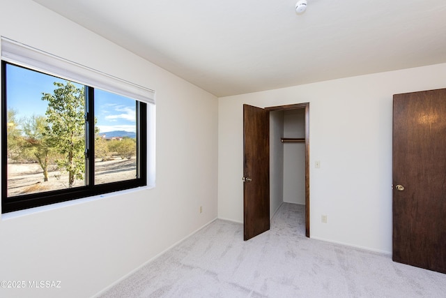 unfurnished bedroom featuring a closet, a walk in closet, and light colored carpet