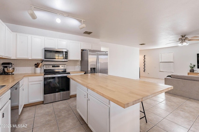 kitchen featuring a center island, a kitchen bar, appliances with stainless steel finishes, white cabinets, and wood counters