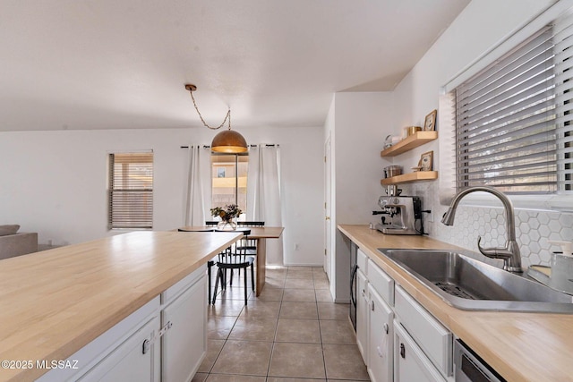 kitchen featuring sink, white cabinetry, decorative light fixtures, and butcher block countertops