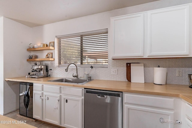 kitchen featuring stainless steel dishwasher, washer / dryer, sink, white cabinetry, and light tile patterned floors