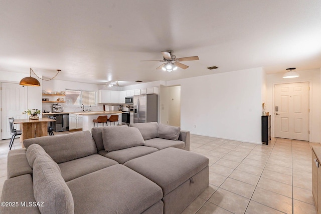 living room with ceiling fan, sink, and light tile patterned floors