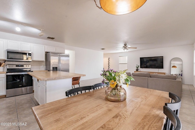 dining space featuring ceiling fan, rail lighting, and light tile patterned floors