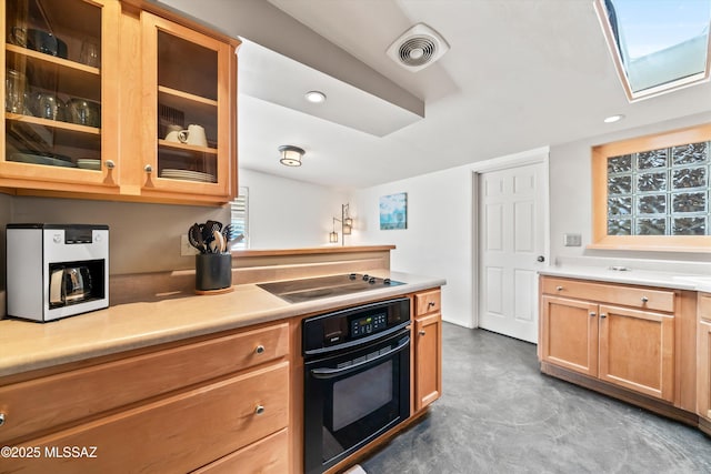 kitchen featuring visible vents, black appliances, light countertops, and glass insert cabinets