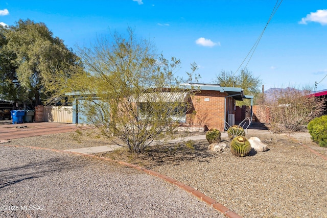 view of front facade with driveway, fence, and brick siding