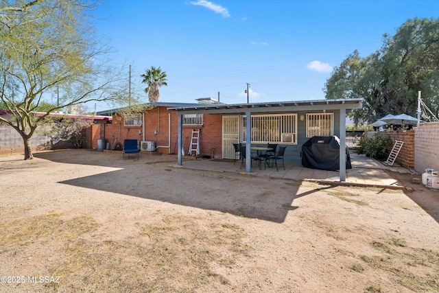 rear view of house featuring brick siding, a fenced backyard, and a patio