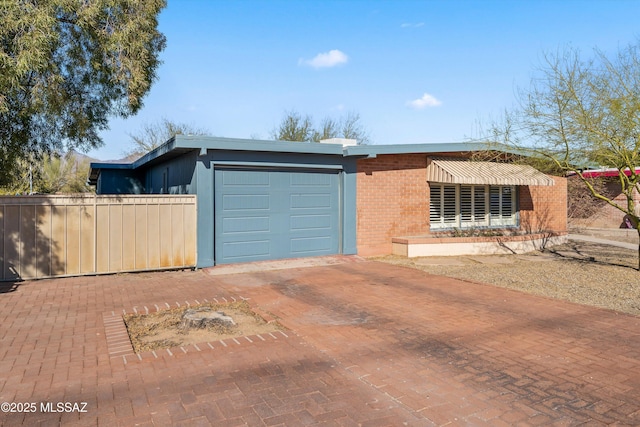 view of front of property with a garage, decorative driveway, brick siding, and fence