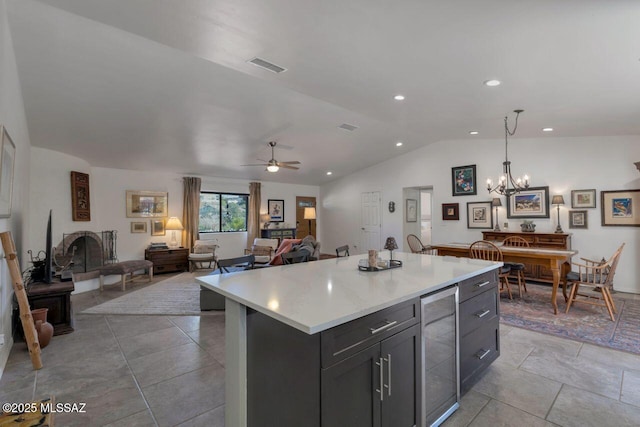 kitchen featuring ceiling fan with notable chandelier, lofted ceiling, a kitchen island, decorative light fixtures, and wine cooler