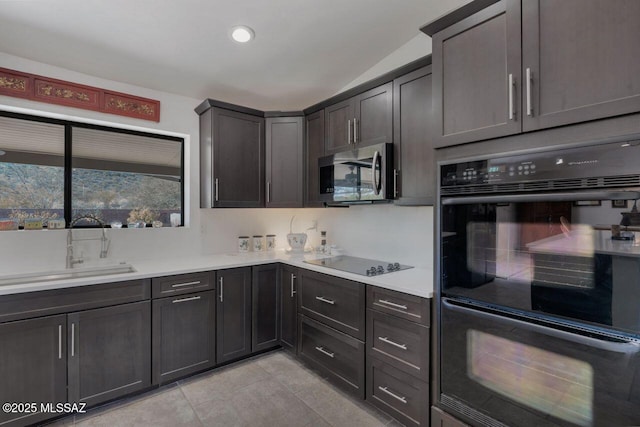 kitchen with dark brown cabinets, sink, light tile patterned floors, black appliances, and lofted ceiling