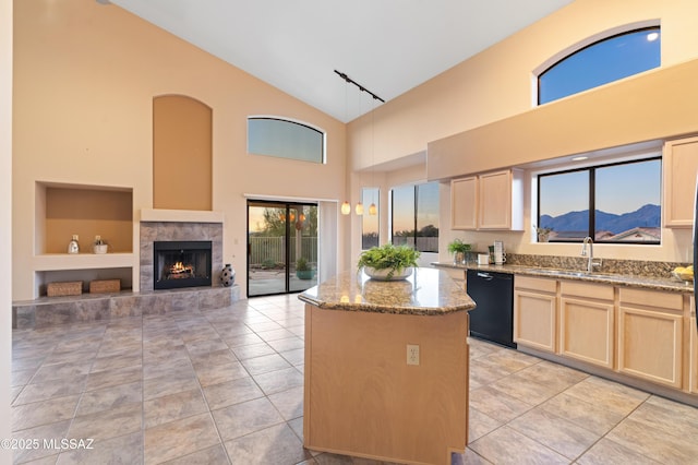 kitchen featuring light stone countertops, a kitchen island, black dishwasher, sink, and a mountain view