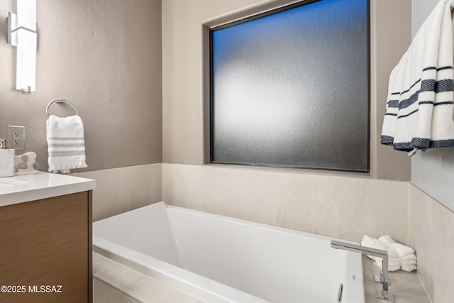 bathroom featuring tiled tub and vanity