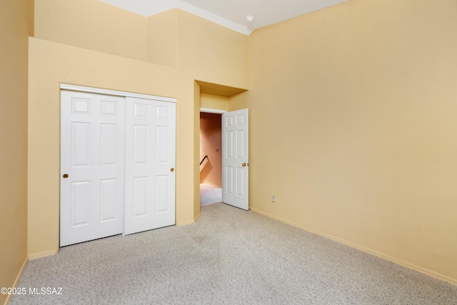 unfurnished bedroom with light colored carpet and a closet