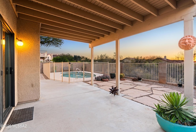 patio terrace at dusk featuring a fenced in pool