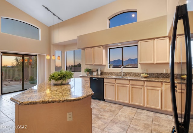 kitchen featuring sink, dishwasher, a kitchen island, and light stone counters