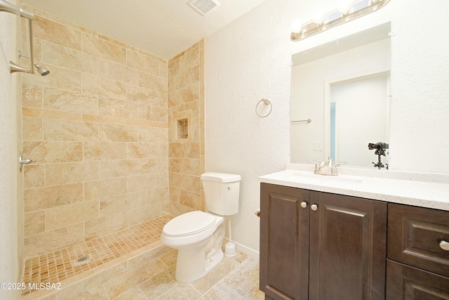 bathroom with toilet, vanity, and tiled shower