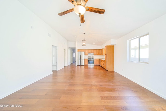 unfurnished living room with ceiling fan, vaulted ceiling, and light wood-type flooring