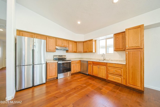 kitchen with light stone countertops, lofted ceiling, stainless steel appliances, sink, and dark hardwood / wood-style floors