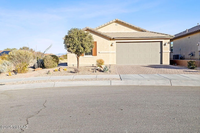 single story home featuring cooling unit and a garage