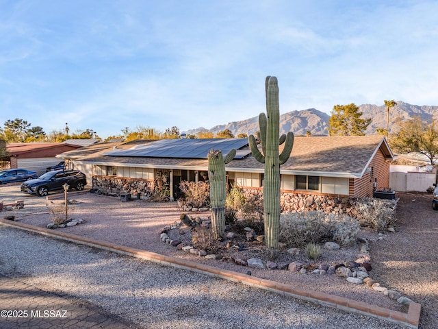 single story home with a mountain view and solar panels