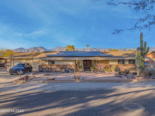 single story home with a mountain view and solar panels