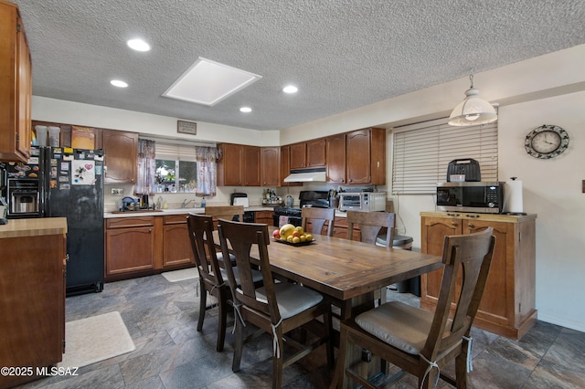 kitchen featuring black fridge, stove, a textured ceiling, and decorative light fixtures