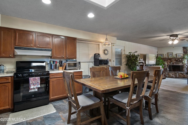 kitchen with ceiling fan, black stove, a fireplace, pendant lighting, and a textured ceiling