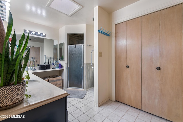 bathroom featuring a shower with door, tile patterned floors, and vanity