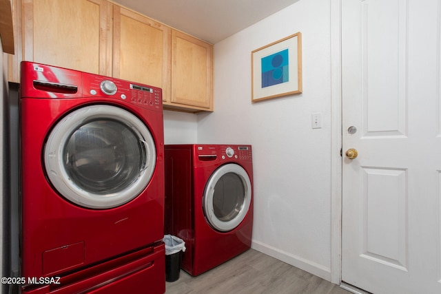 washroom featuring cabinets, washer and clothes dryer, and light hardwood / wood-style flooring