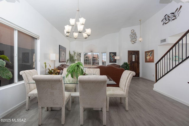 dining space featuring hardwood / wood-style flooring, high vaulted ceiling, and a chandelier