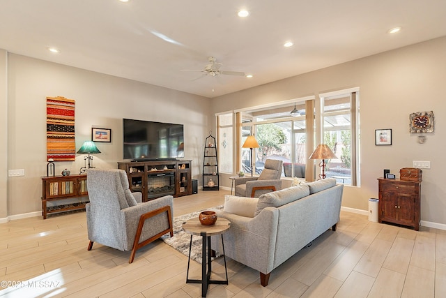 living room with a fireplace, light hardwood / wood-style flooring, and ceiling fan