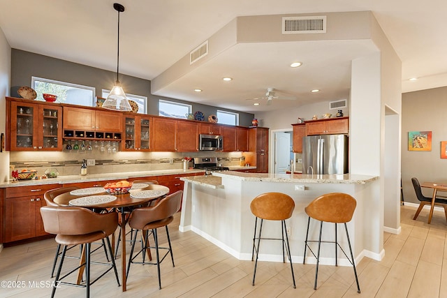 kitchen with appliances with stainless steel finishes, a kitchen breakfast bar, light stone countertops, and decorative backsplash