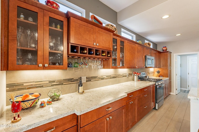 kitchen with stainless steel appliances, light stone countertops, and backsplash