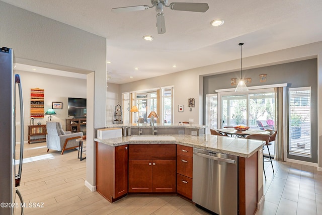 kitchen featuring sink, light wood-type flooring, pendant lighting, stainless steel appliances, and light stone countertops