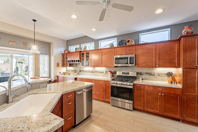 kitchen with sink, backsplash, hanging light fixtures, stainless steel appliances, and a healthy amount of sunlight