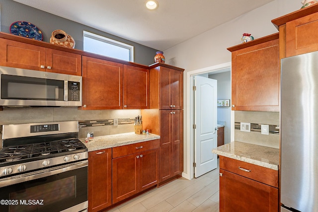 kitchen with tasteful backsplash, stainless steel appliances, and light stone countertops