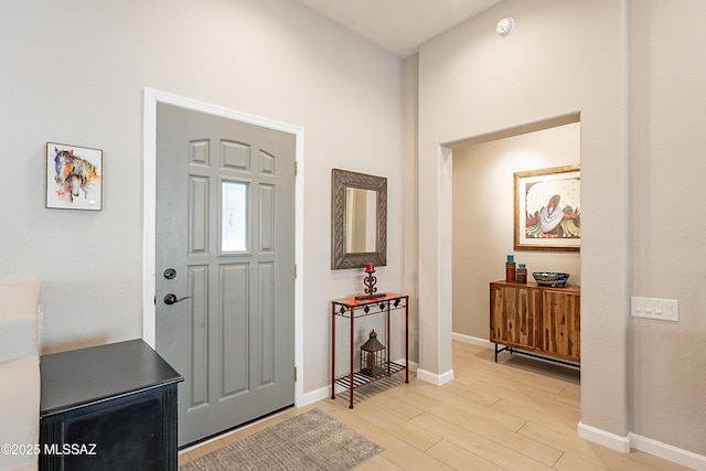 foyer featuring a towering ceiling and light hardwood / wood-style floors