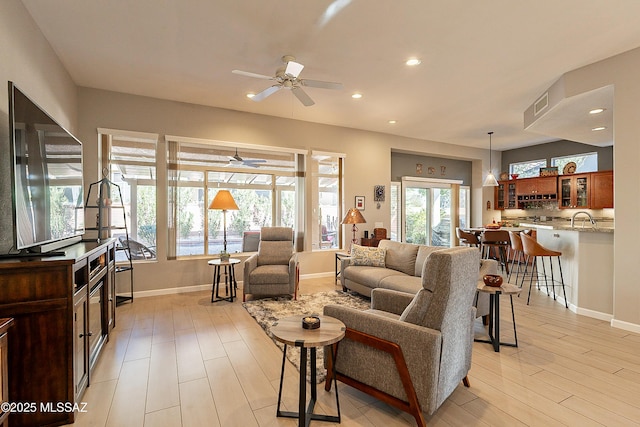 living room with ceiling fan, light hardwood / wood-style floors, sink, and a wealth of natural light