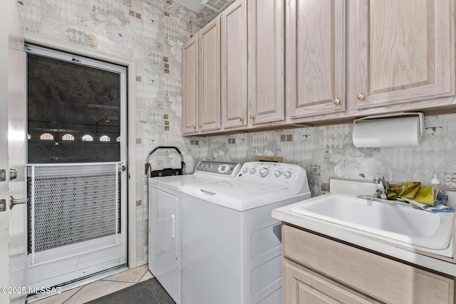 laundry room with cabinets, washing machine and clothes dryer, sink, and light tile patterned floors